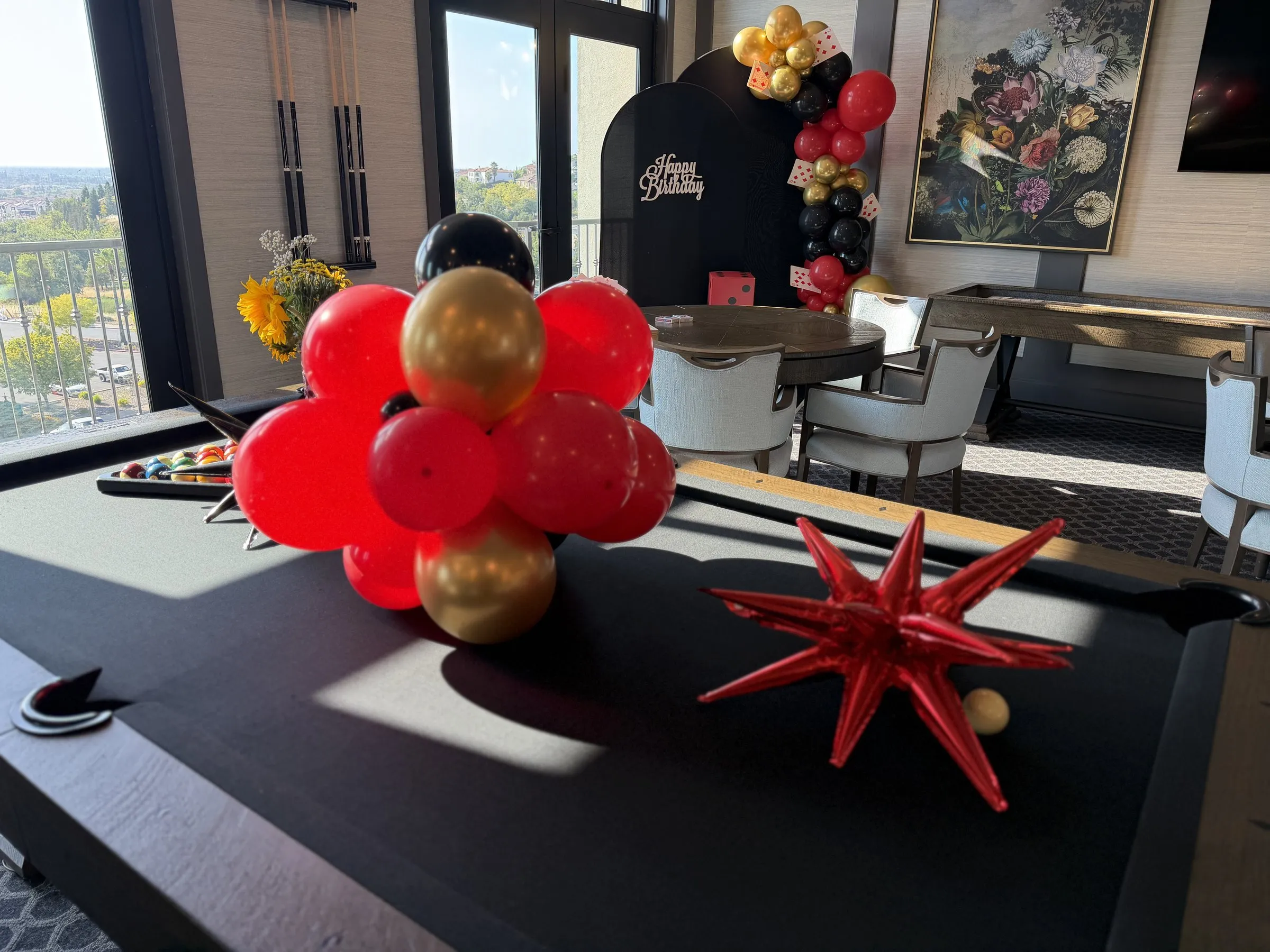 Red and gold balloon centerpiece cluster with a red starburst accent arranged on a poker table