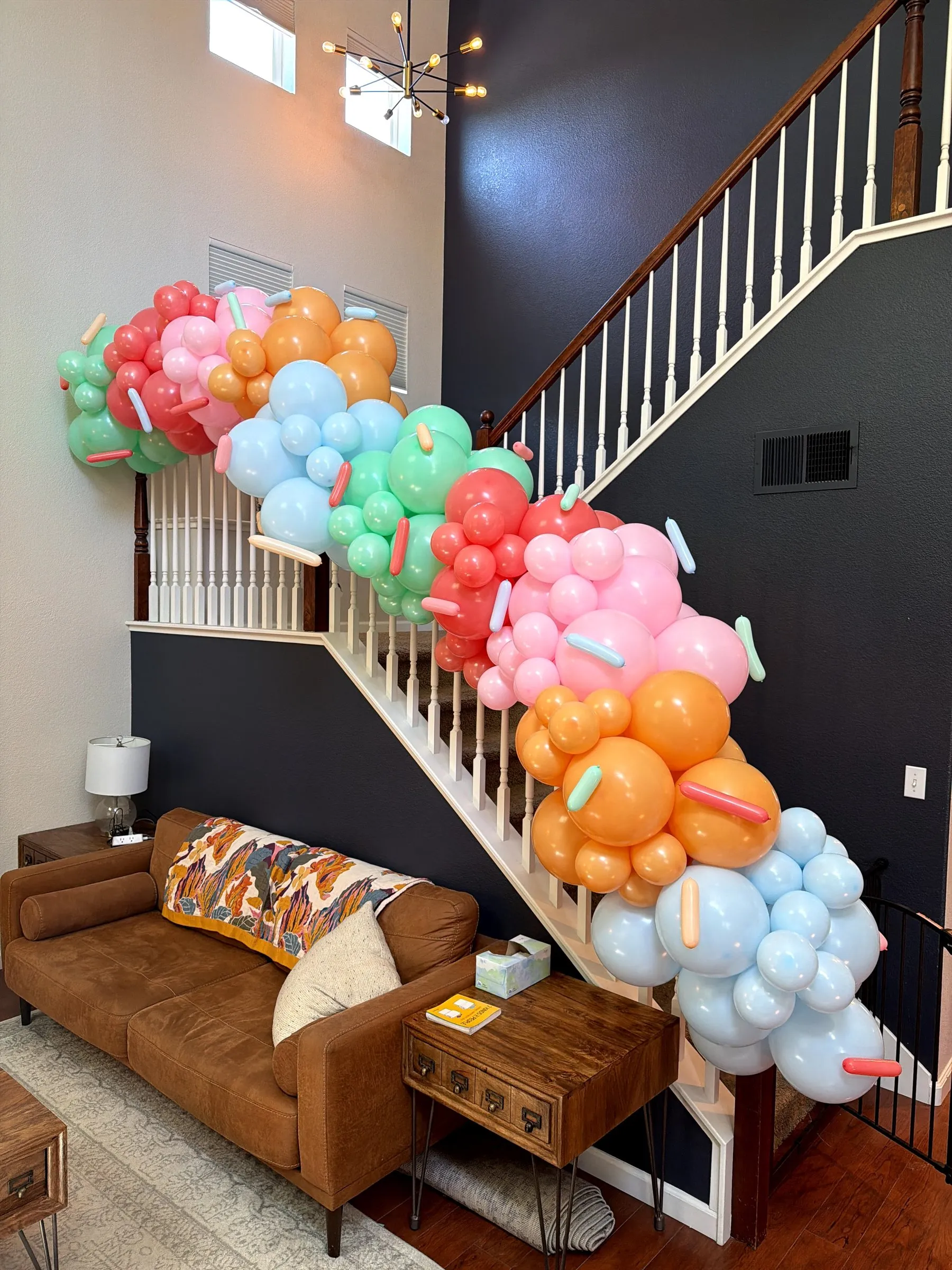 Pastel organic balloon garland in mint, coral, pink and orange cascading down a staircase banister at a Sacramento children's birthday party